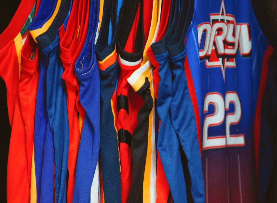 Colorful San Marcos custom apparel with sports jerseys hanging in a row.